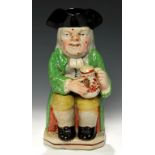 A STAFFORDSHIRE EARTHENWARE TOBY JUG, C1820-30 with warty face in bright green coat, 24cm h++Pipe