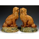 PAIR OF SCOTTISH OCHRE GLAZED EARTHENWARE MODELS OF SPANIELS, 19TH C the oval base with blue,