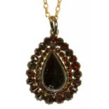 A CLOSED BACK PEAR SHAPED GARNET CABOCHON PENDANT ON LATER 9CT GOLD CHAIN, THE CENTRAL CABOCHON