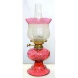 A VICTORIAN WRYTHEN FLUTED AND TRAILED CRANBERRY GLASS OIL LAMP OF BELL SHAPE, WITH BRASS BURNER,