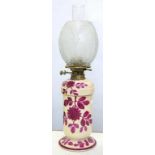 A VICTORIAN CREAM EARTHENWARE OIL LAMP AND BASE, PAINTED WITH PURPLE FLOWERS, BRASS BURNER,