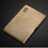 CARTIER. AN ART DECO 9CT GOLD CIGARETTE CASE diagonally reeded, the lid applied with arms of