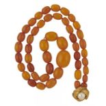 A NECKLACE OF FORTY-EIGHT AMBER BEADS 34g excluding later plated button