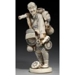 A JAPANESE IVORY OKIMONO OF A BASKET SELLER, TAISHO PERIOD in the form of a smiling man carrying