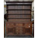 AN EARLY 19TH C OAK DRESSER WITH RACK, NORTH WALES, THE BASE FITTED WITH PANELLED DOORS, 210CM H X