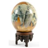 AN OSTRICH EGG DECORATED WITH COLOUR PRINTS OF WILD ANIMALS, GILT AND VARNISHED, 14CM H, CARVED WOOD