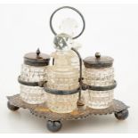 A VICTORIAN EMBOSSED SILVER CRUET STAND AND FOUR CUT GLASS CONDIMENT BOTTLES AND STOPPERS, INCLUDING