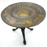 AN INDIAN PEACOCK DECORATED BRASS COFFEE TABLE ON CARVED AND STAINED WOOD ENTWINED LEGS, 75CM D,