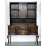 A DARK STAINED OAK DRESSER, THE BOARDED RACK WITH CENTRAL SPICE CUPBOARD, ON CABRIOLE LEGS, 136CM L,