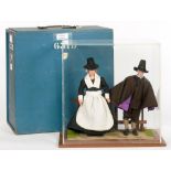 COSTUME DOLLS. A PURITAN COUPLE IN ACRYLIC DISPLAY CASE ON WOOD BASE, 38CM H, IN PAINTED WOOD