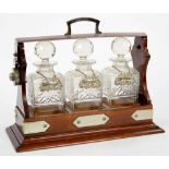 A VICTORIAN MAHOGANY AND PLATED TANTALUS, 35 CM W, WITH THREE GLASS DECANTERS AND THREE GEORGE III