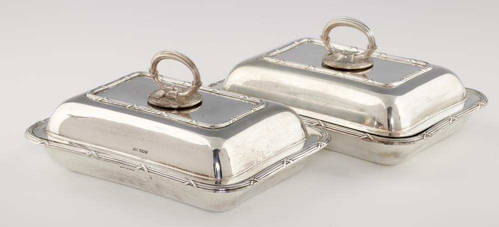 A PAIR OF GEORGE V SILVER ENTREE DISHES AND COVERS with ribbon and reed rims, 28cm l, by Walker &