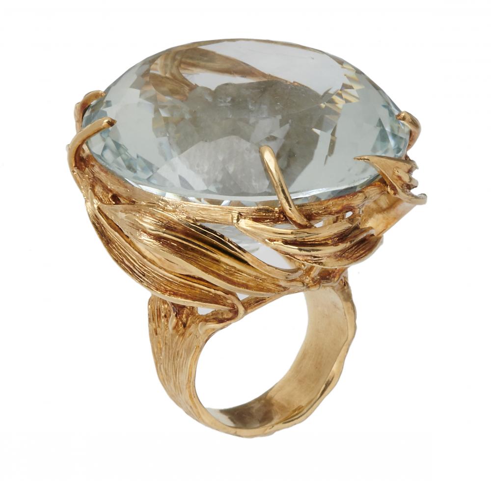 A BLUE TOPAZ COCKTAIL RING the round faceted topaz approx 110 ct, in rustic textured gold hoop, 46g,