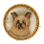 A VICTORIAN REVERSE PAINTED CRYSTAL INTAGLIO BROOCH OF A TERRIER in gold mount, 2.3 cm diameter, 6.