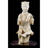 A JAPANESE IVORY OKIMONO OF A SEATED MAN, WOOD BASE, 16CM H, MEIJI PERIOD