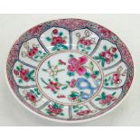 A CHINESE FAMILLE ROSE 'RUBY BACK' SAUCER, PAINTED IN THE CENTRE WITH FLOWERS GROWING FROM A BLUE