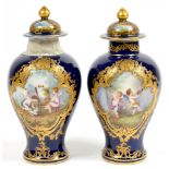 A PAIR OF SEVRES STYLE COBALT GROUND VASES AND COVERS, PAINTED WITH PUTTI IN RAISED GILT