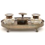 A VICTORIAN OVAL EPNS GALLERY INKSTAND WITH TAPER STICK, WAFER COMPARTMENT AND TWO CUT GLASS