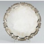 A VICTORIAN SILVER SALVER on three volute feet, 25.5cm diam, by W Hutton & Sons Ltd, London 1895,