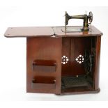 A STANDARD TREADLE MACHINE IN CABINET, FOLDS DOWN INTO BASE UNIT