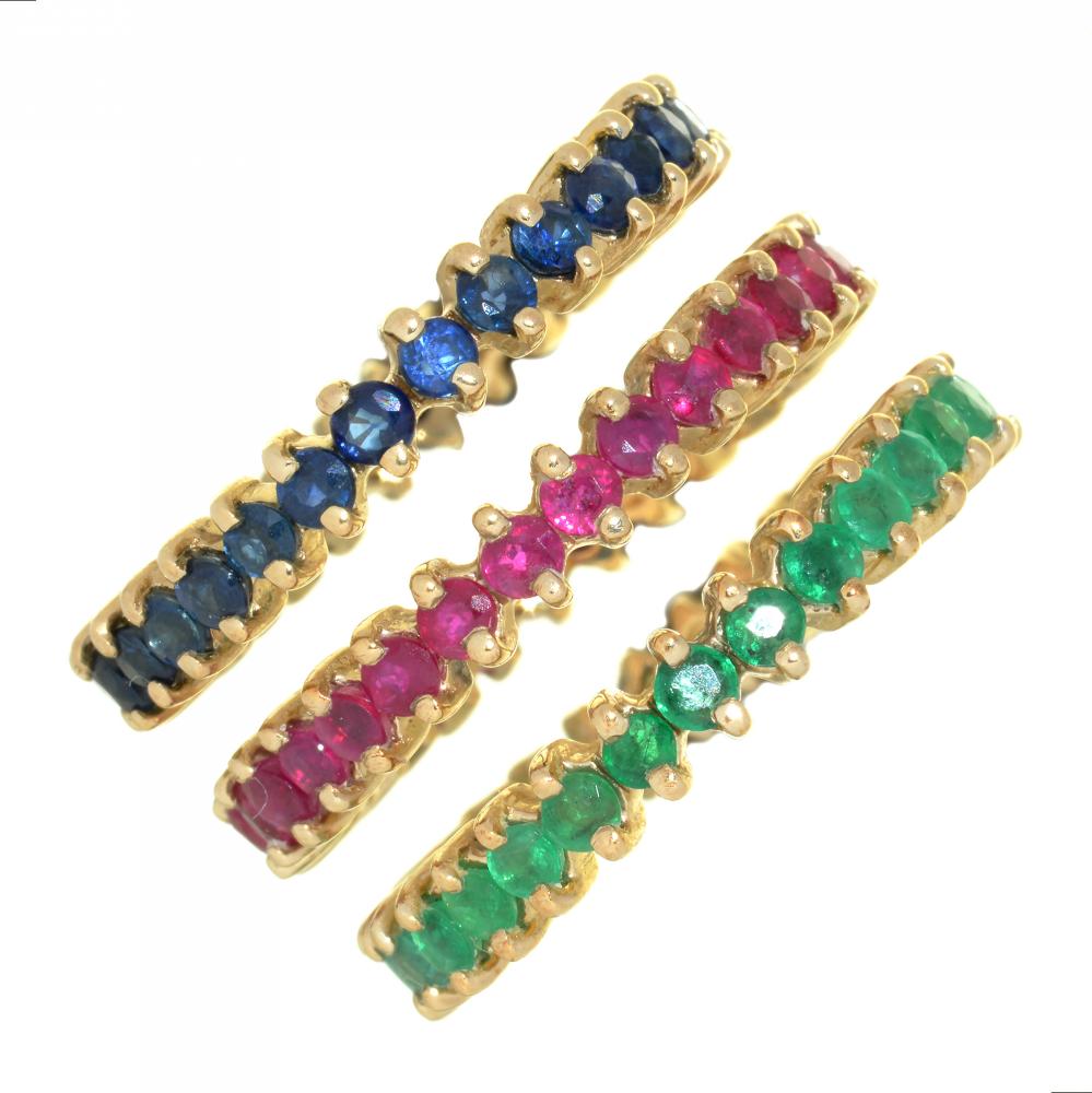 A HARLEQUIN GROUP OF THREE ETERNITY RINGS, WITH EMERALDS, RUBIES AND SAPPHIRES, IN GOLD MARKED 9K,
