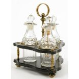 A VICTORIAN BRASS MOUNTED TRIANGULAR PAPIER MACHE CRUET FRAME AND THREE CONTEMPORARY CUT GLASS