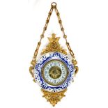 A GILTMETAL MOUNTED BLUE AND WHITE EARTHENWARE HANGING TIMEPIECE WITH FENESTRATED DIAL, SPRING