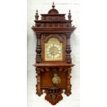 AN ORNATE GERMAN WALNUT WALL CLOCK WITH EMBOSSED BRASS BREAKARCHED DIAL AND PRIMROSE ENAMEL