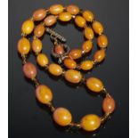 A NECKLACE OF TWENTY NINE AMBER BEADS WITH AMBER GLASS SPACERS 30g Good condition