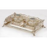 A GEORGE V SILVER INKSTAND  with saw pierced gallery and pair of silver mounted glass wells, 26cm l,