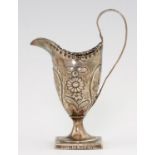 A GEORGE III HELMET SHAPED SILVER CREAM JUG chased with a sunflower to either side, the foot