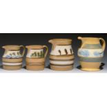 FOUR MOCHA WARE JUGS, 19TH C of buff earthenware with white slip bands, one in blue and sepia, the