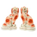 A PAIR OF STAFFORDSHIRE EARTHENWARE MODELS OF SEATED SPANIELS, C1860  with free foreleg and