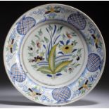 A DUTCH DELFTWARE POLYCHROME DISH, LATE 18TH C painted with flowers and hedge, 32cm diam, painted