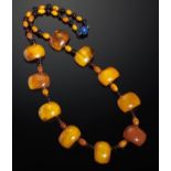 A NECKLACE OF TEN FLAT SIDED AMBER BEADS AND SMALLER AMBER BEADS ALTERNATING WITH CHERRY AMBER ROUND