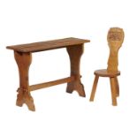 A THOMAS 'GNOMEMAN' WHITTAKER OAK TRESTLE ENDED TABLE AND A SPINNING CHAIR, BOTH 1960-70S table with