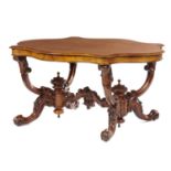 A VICTORIAN WALNUT CENTRE TABLE, C1860  the serpentine butterfly veneered top on profusely carved