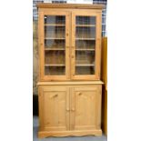 A WAXED PINE BOOKCASE, THE UPPER PART WITH ADJUSTABLE SHELVES, ENCLOSED BY GLAZED DOORS, 198CM H; 98