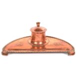 AN ARTS AND CRAFTS COPPER INKWELL ON THREE BRACKET FEET, 25CM L, C1910