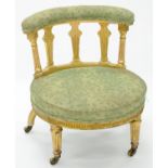 A VICTORIAN GILTWOOD AND COMPOSITION NURSING CHAIR ON BRASS CASTORS, WITH GREEN UPHOLSTERY