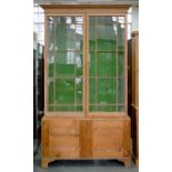 A VICTORIAN WAXED PINE BOOKCASE, THE UPPER PART ENCLOSED BY GLAZED DOORS, 236CM H; 137CM W