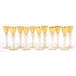 A SET OF ELEVEN GILT GLASS LIQUEURS WITH BELL SHAPED BOWL ON SEMI OPALESCENT FEMALE FIGURAL STEM