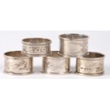 A SET OF FOUR GEORGE V SILVER NAPKIN RINGS, BIRMINGHAM 1915 AND A VICTORIAN SILVER NAPKIN RING,