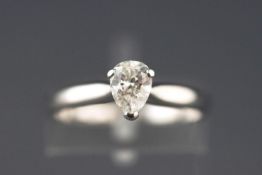 A white metal single stone ring set with a pear brilliant cut diamond.