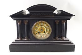 A black stone Temple style mantel clock with four brass topped corinthian columns