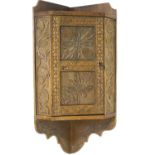 A small carved oak wall hanging cupboard with high relief floral and foliate decoration,
