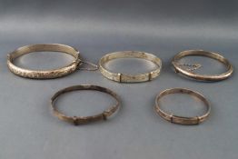 A collection of five silver bangles of variable designs. All marked/hallmarked as sterling silver.