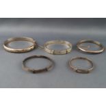 A collection of five silver bangles of variable designs. All marked/hallmarked as sterling silver.