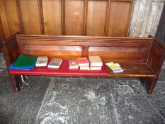 A Victorian pine pew with double paneled back and prayer book shelf to reverse with one damaged end