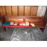 A Victorian pine pew with double paneled back and prayer book shelf to reverse with one damaged end